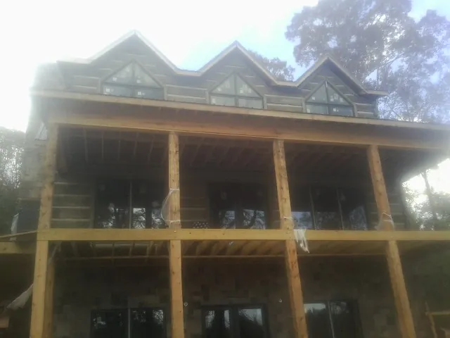 Dormers and porch framing on a large log home under construction — Roof Coating work by our crew in Dry Fork