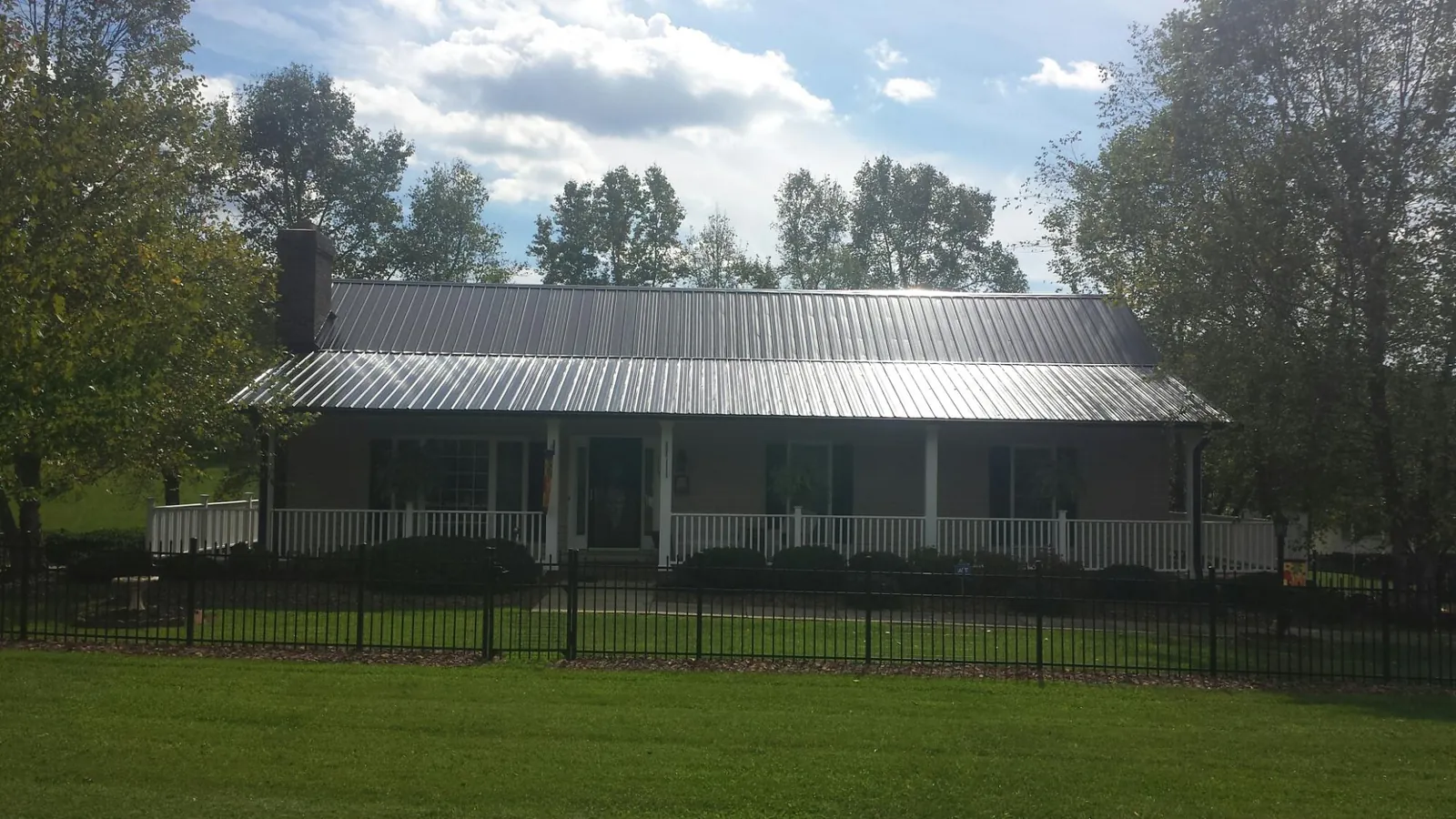 Gray metal roof on a brick ranch with a full width front porch — Gutter Guard Installation work by our crew in Dry Fork